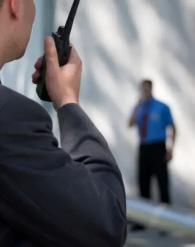Deux agents de sécurité en communication via talkie-walkie, assurant la sécurité et la coordination lors d’un événement ou sur un site professionnel.